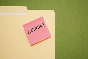 Folder with pink sticky note reading lunch on a green background.