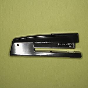 Black stapler on green background