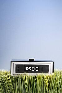 Studio shot of retro alarm clock placed in grass.