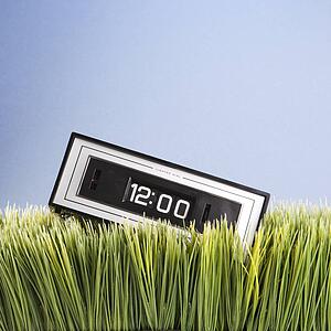 Studio shot of retro alarm clock placed in grass
