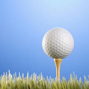 Studio shot of a golfball on a tee in grass.