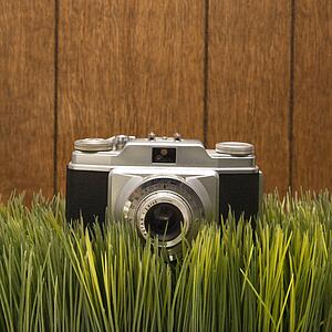 Studio shot of vintage camera with wood paneling in background.