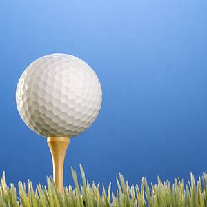 Studio shot of a golfball on a tee in grass.
