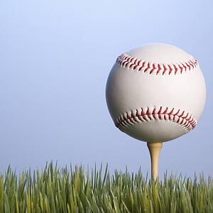 Studio shot of baseball resting on golf tee in grass.
