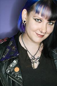 Portrait of woman with blue hair and black leather jacket against blue background