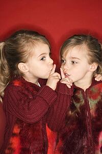 Twins with fingers up to lips
