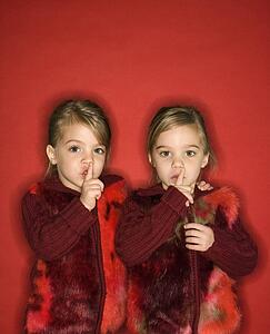 Twins with fingers up to lips
