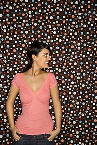 Young adult female Caucasian looking to side on polka dot background.