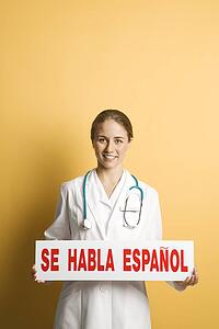 Female doctor holding up se habla espanol sign