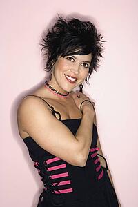 Portrait of smiling Hispanic woman standing against pink background.