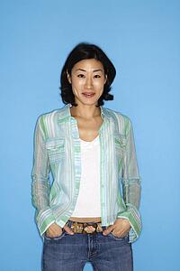 Half length portrait of pretty Asian mid adult woman on blue background.