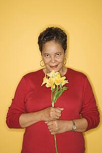 African American mature adult female holding flowers.