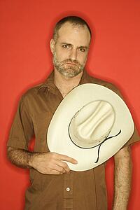 Man with beard and receding hairline holding cowboy hat