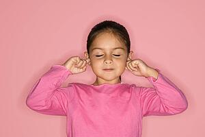 Girl with fingers in ears and eyes closed