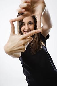 Portrait of female smiling with hands in foreground.