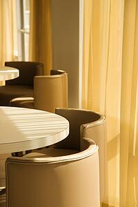Warm toned table and chairs by window with drapes
