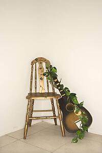 Still life of guitar with garland leaning against a chair.