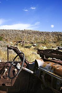 Driver's wheel of old abandoned and rusted car in field