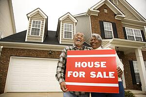 Couple outside house with for sale sign