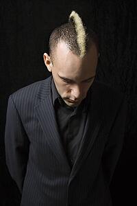 Man in suit with mohawk looking down 