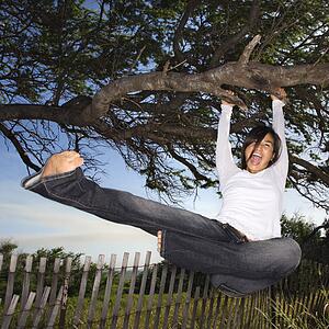 Female holding on to tree and kicking air and screaming