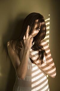 Portrait of pretty Caucasian young woman standing against wall giving middle finger.
