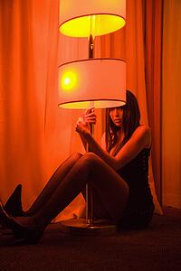 Woman sitting on floor holding floor lamp