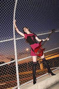 Young adult female holding electric guitar in skywalk