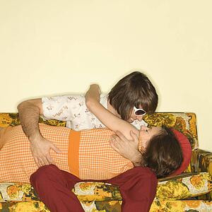 Couple smiling and embracing on colorful retro sofa.