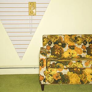 Retro floral printed sofa with yellow rotary phone hanging on wall.