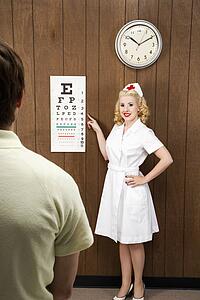 Female nurse pointing out eye chart to mid-adult male patient