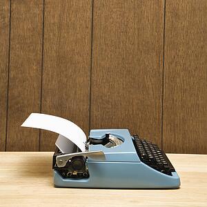 Vintage blue typewriter on desk with wood paneling.