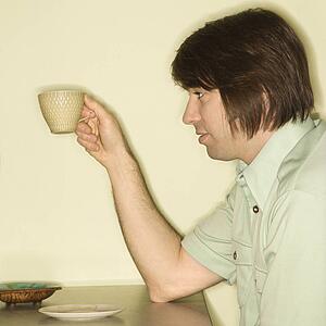 Side view of mid-adult man holding up coffee cup