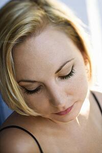Caucasian mid-adult blonde woman looking down.