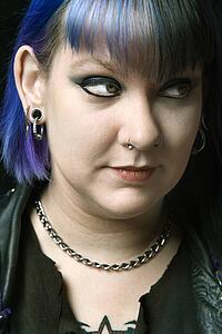 Head shot of woman with blue hair looking off to side