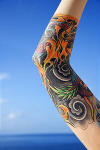 Close up of tattooed woman's arm with Pacific Ocean in background 