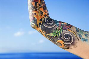 Close up of tattooed woman's arm with Pacific Ocean in background 