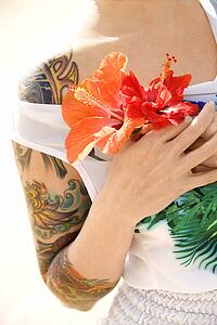 Tattooed woman holding Hibiscus flowers 