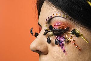 Close-up of woman in unique makeup against orange background
