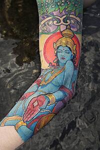 Arm of tattooed Caucasian woman by tidal pool 