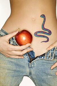 Portrait of attractive young woman holding apple by snake tattoo on stomach