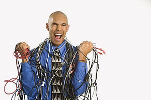 Frustrated businessman wrapped in cords
