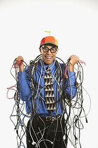 Businessman wrapped in computer cables wearing nerd hat and glasses