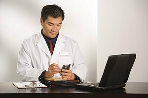 Man in a lab coat checking his phone