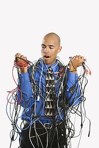 Confused businessman tangled in cables