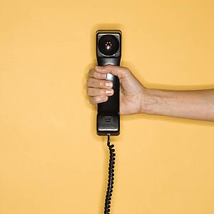Close up of woman holding telephone receiver on yellow background