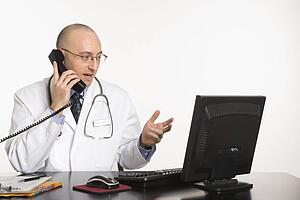 Doctor looking at a computer while talking on a phone