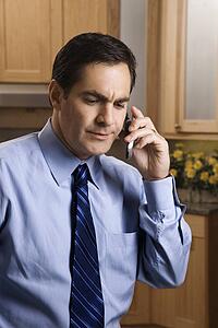 Man in business apparel on a cellphone in the kitchen