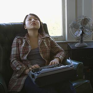 Young woman with a typewriter on her lap sitting in an armchair