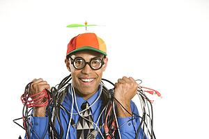 Businessman in silly hat holding tangled cords